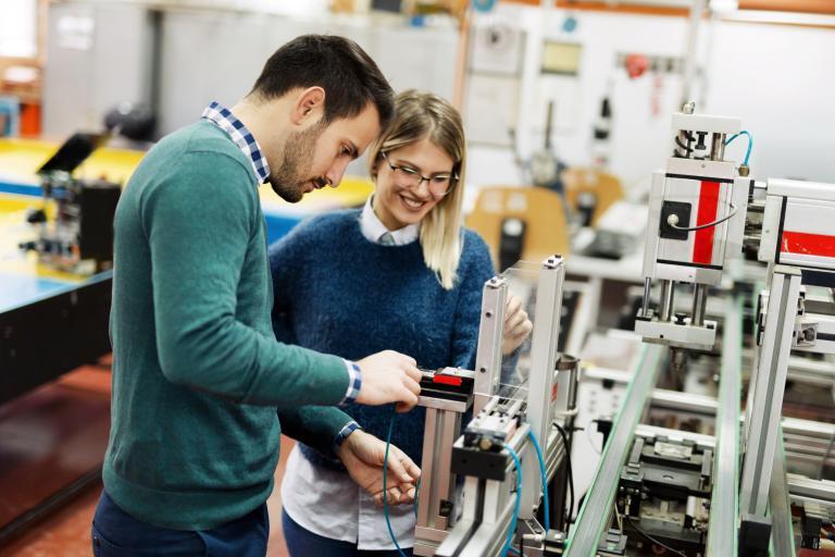 Two people work in an industrial lab environment.